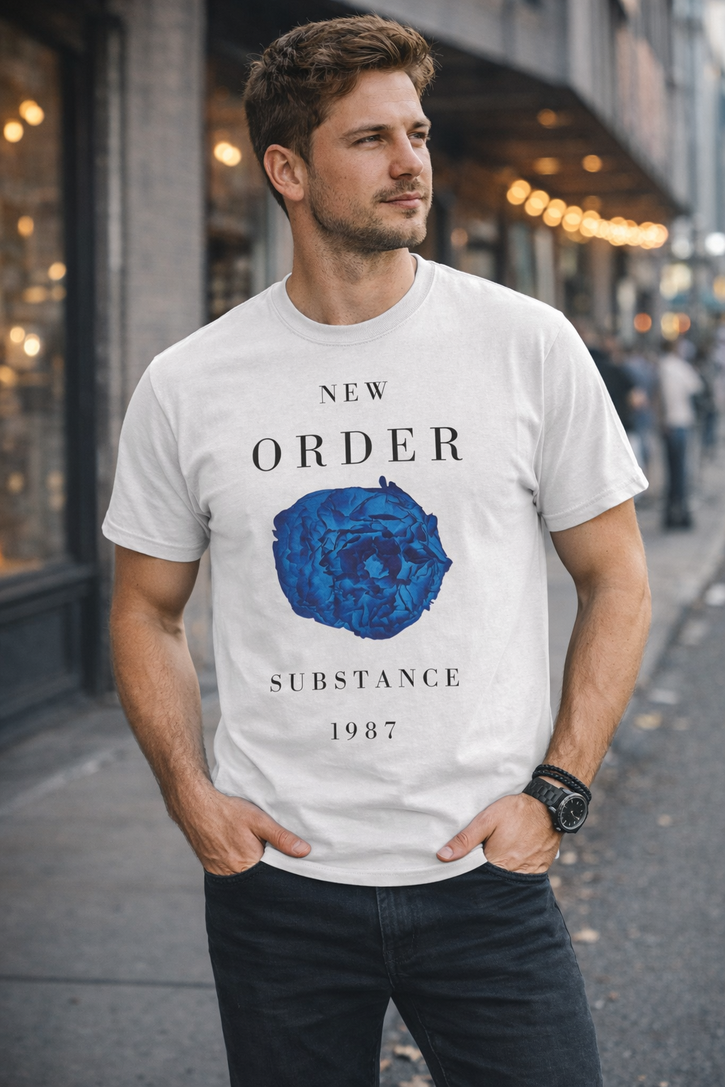 Male model wearing New Order Substance 1987 t-shirt with blue flower design in urban street setting