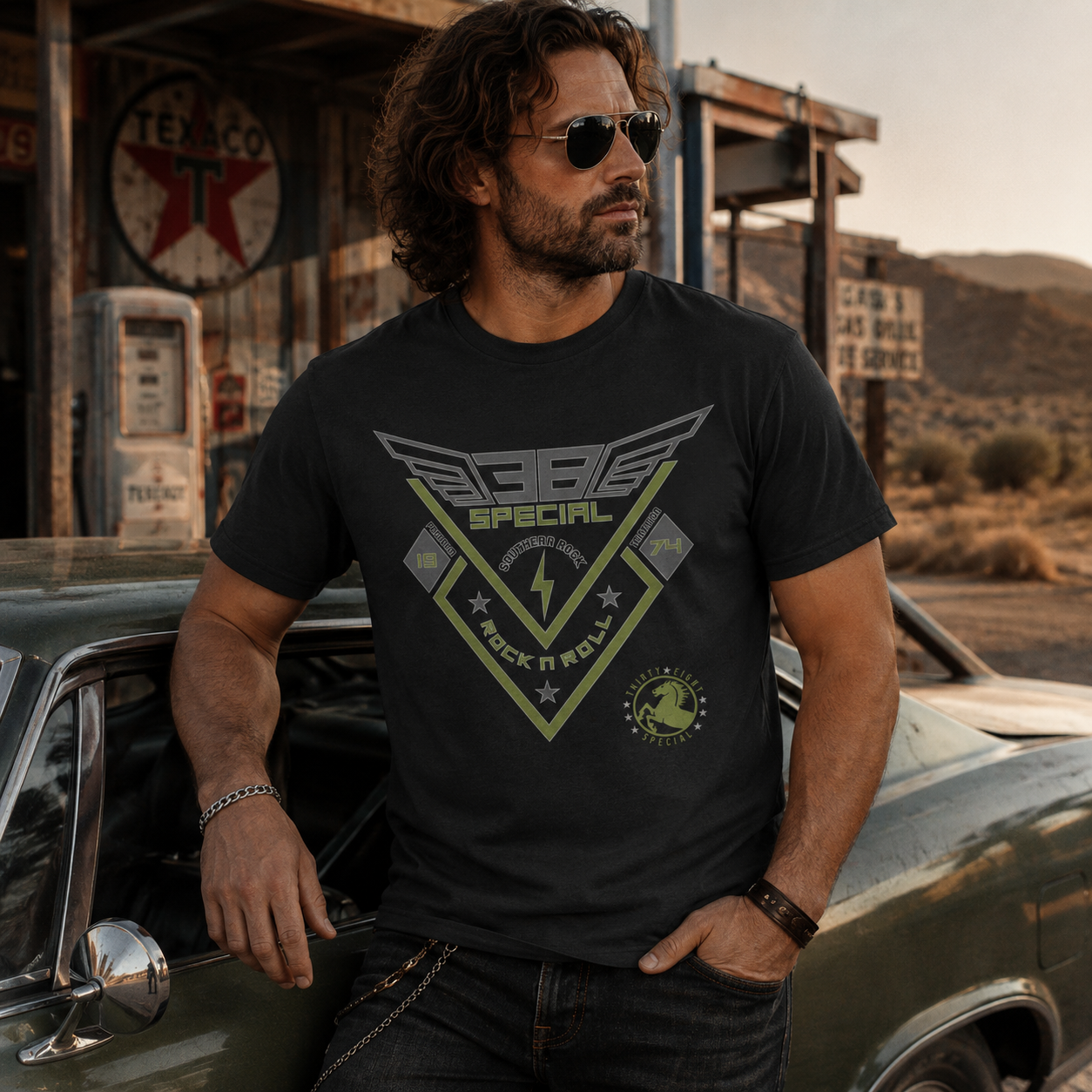 Male model wearing a black 38 Special Rock & Roll '74 T-Shirt while leaning against a vintage muscle car outside a rustic desert roadside garage, showcasing Southern rock style and officially licensed 38 Special band merchandise.