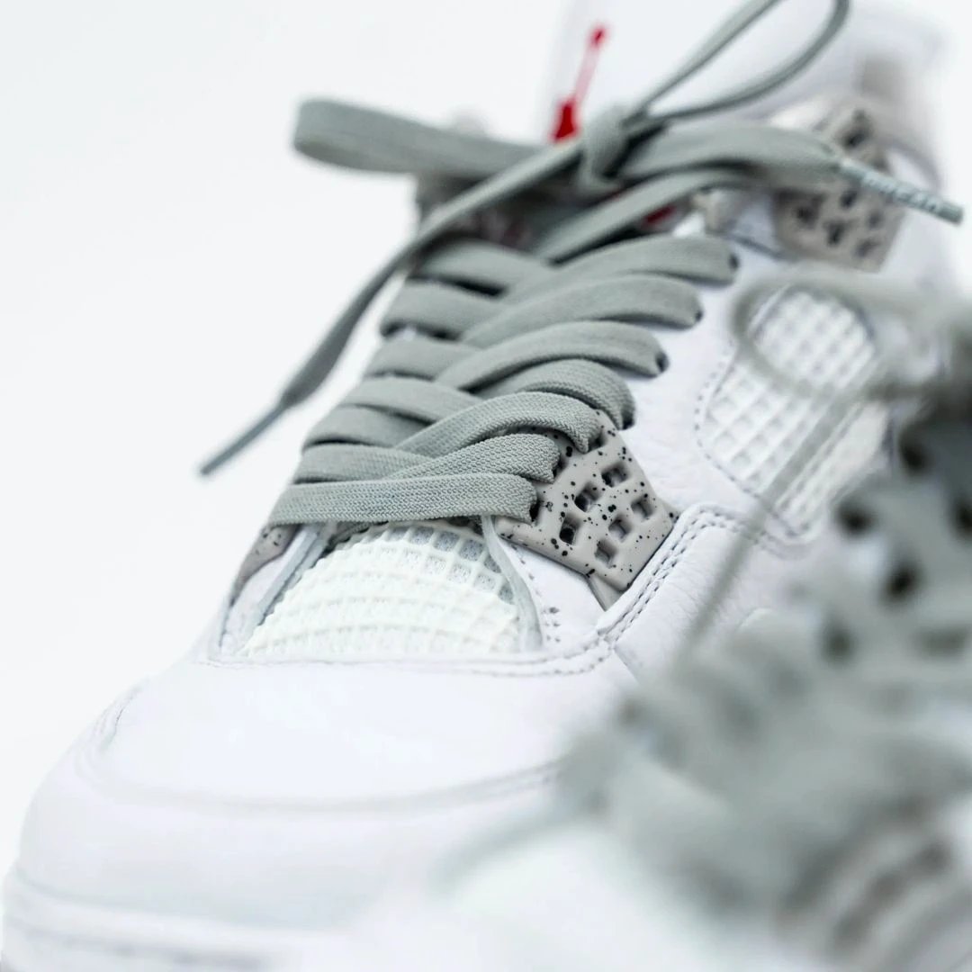Close-up of a white sneaker with gray laces on a blurred background