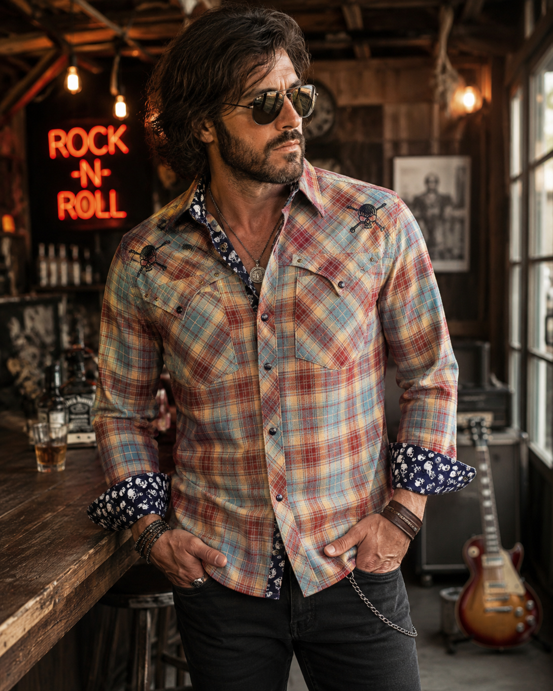 Male model wearing a blue skull western flannel shirt in a rock bar setting with rolled cuffs, plaid fabric, and rock-inspired style