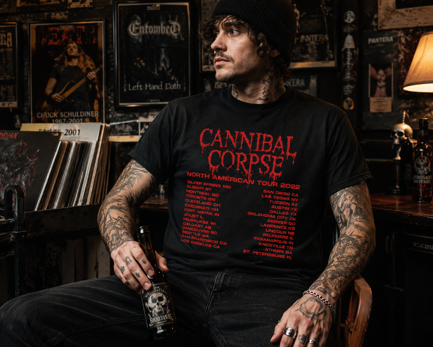Male model wearing Cannibal Corpse North American Tour 2022 black t-shirt inside dark metal-themed room with concert posters and vinyl records