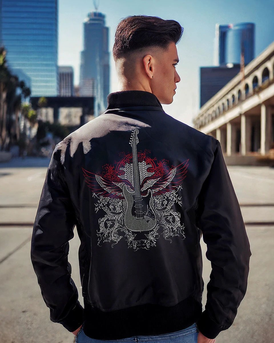 Back view of male model wearing black guitar bomber jacket featuring embroidered guitar artwork and rock-inspired fashion styling in an urban city setting