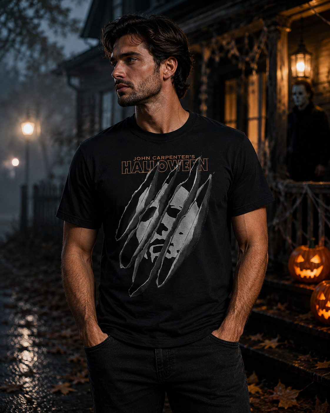 Male model wearing a Halloween torn mask horror tee outside a dark Halloween house with glowing pumpkins, fog, and porch lights.