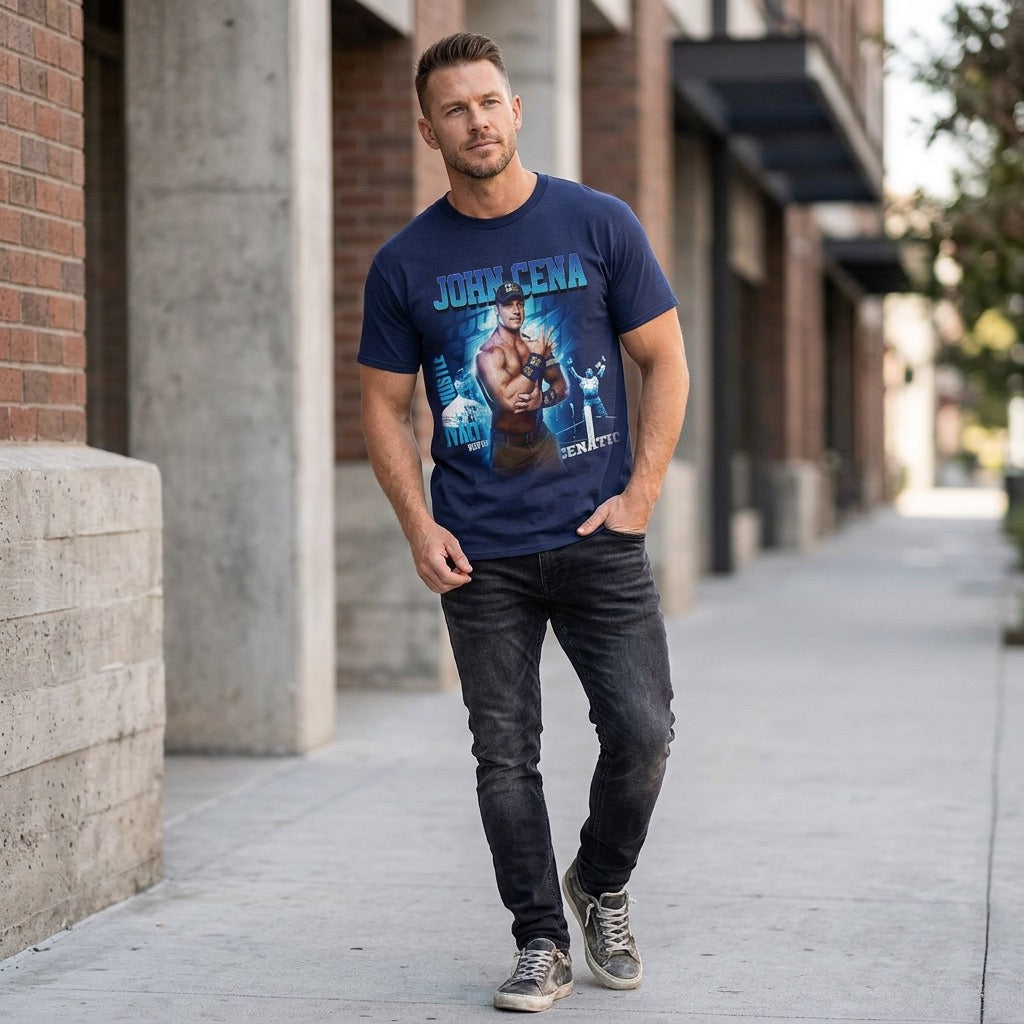 Male model wearing a navy WWE John Cena graphic t-shirt while walking on a city sidewalk. The officially licensed wrestling tee features a colorful John Cena graphic with bold lettering and action artwork, styled with dark jeans in an urban lifestyle setting.