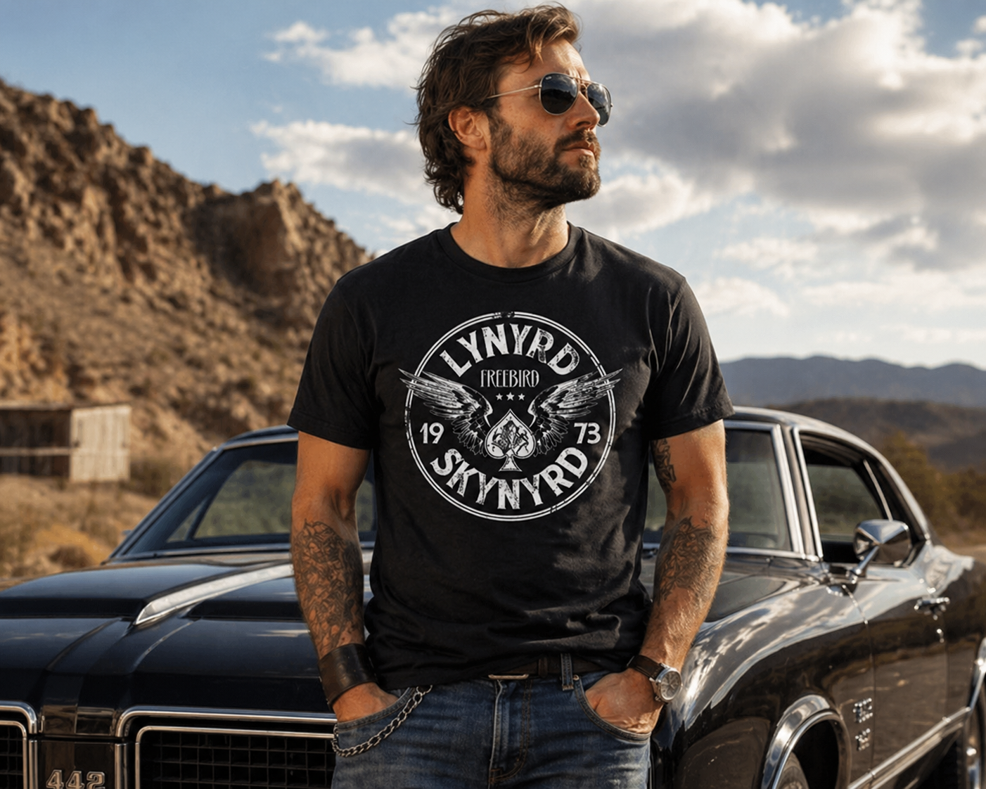 male model wearing Lynyrd Skynyrd Free Bird 1973 black t shirt standing by muscle car in desert setting