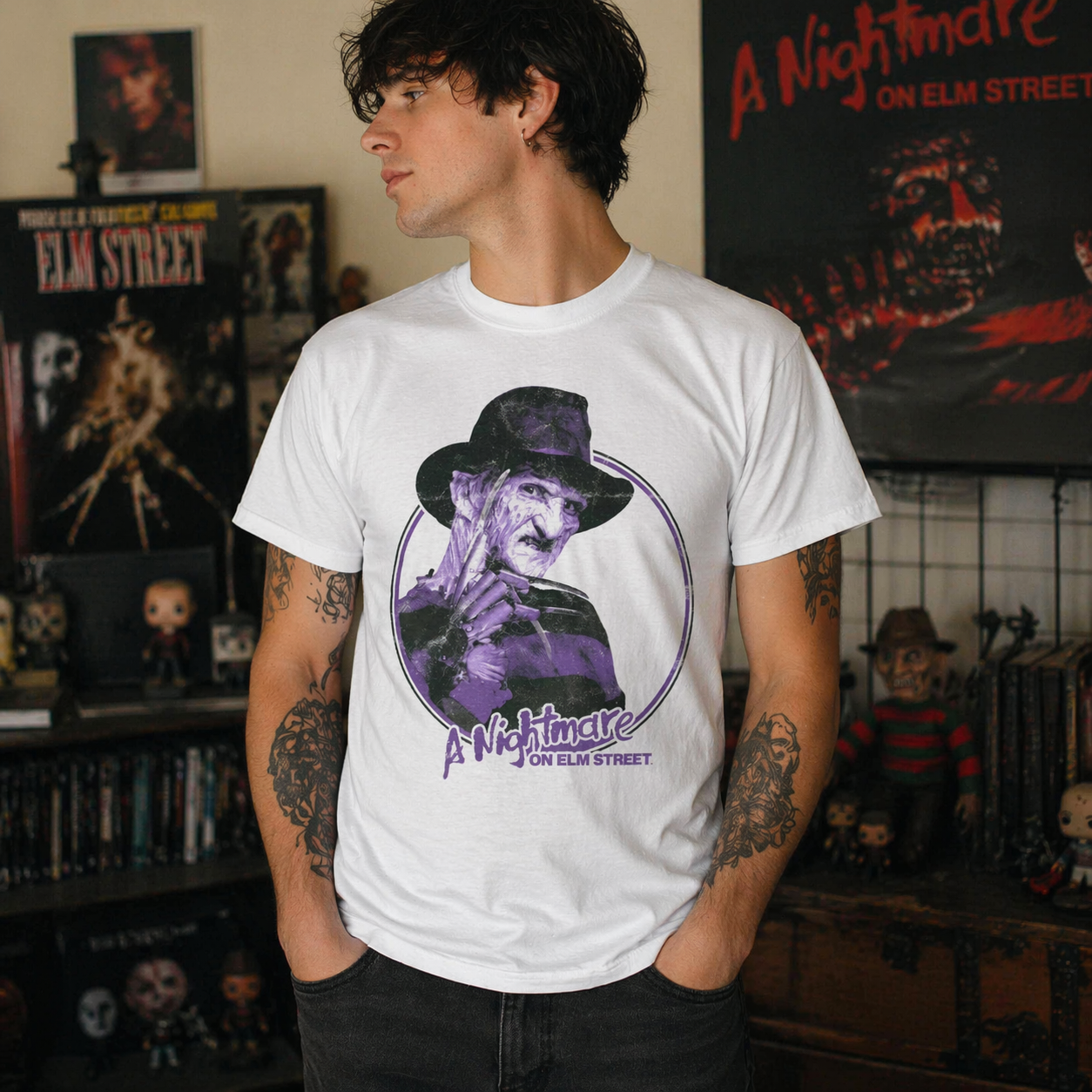 Male model wearing Nightmare on Elm Street Freddy Krueger purple graphic t-shirt in horror-themed room