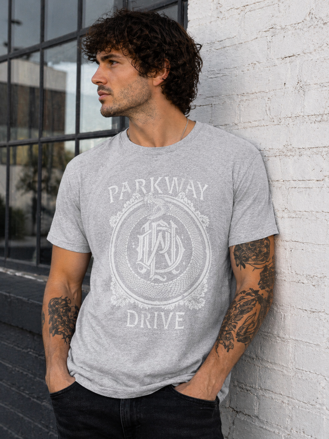 male model wearing Parkway Drive grey snake monogram t shirt in urban street style setting metalcore band merch