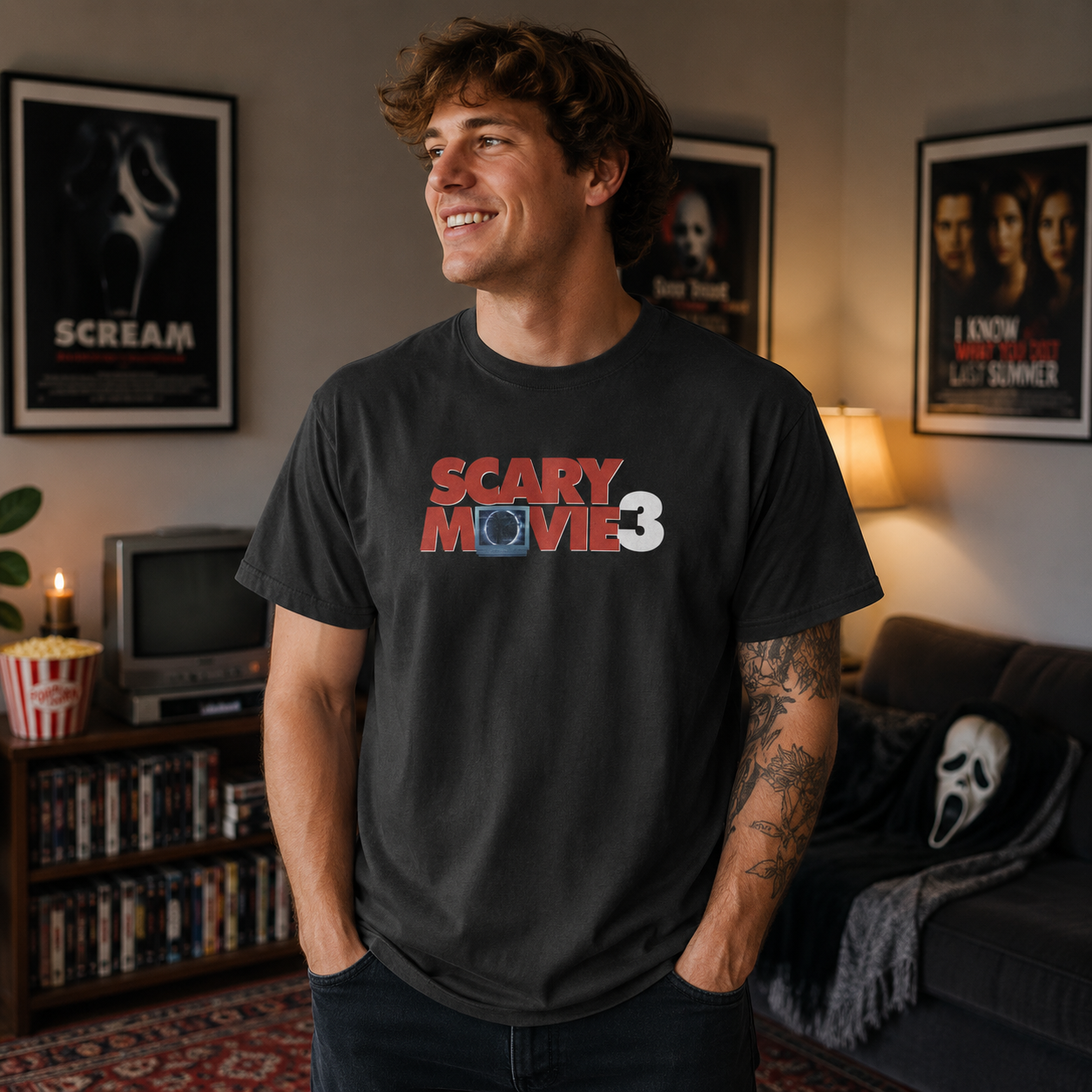 Male model wearing Scary Movie 3 Logo Black T-Shirt in a horror movie themed room with posters and vintage TV