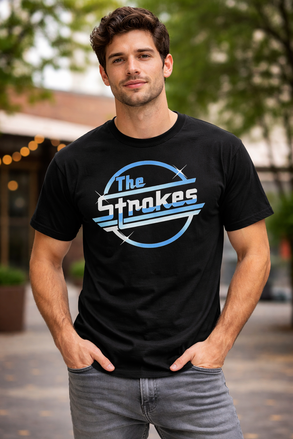 Male model wearing an officially licensed The Strokes logo t-shirt featuring a blue and white circular band design on a black tee, photographed outdoors in a casual urban setting for indie rock and alternative music fans.