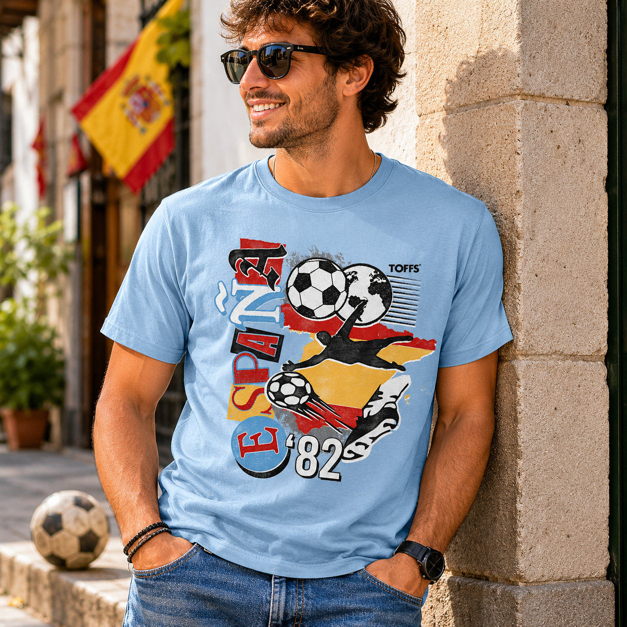 Male model wearing Toffs Retro Soccer Spain Light Blue T-Shirt featuring España 82 futbol artwork, vintage soccer graphics, and casual match day style.