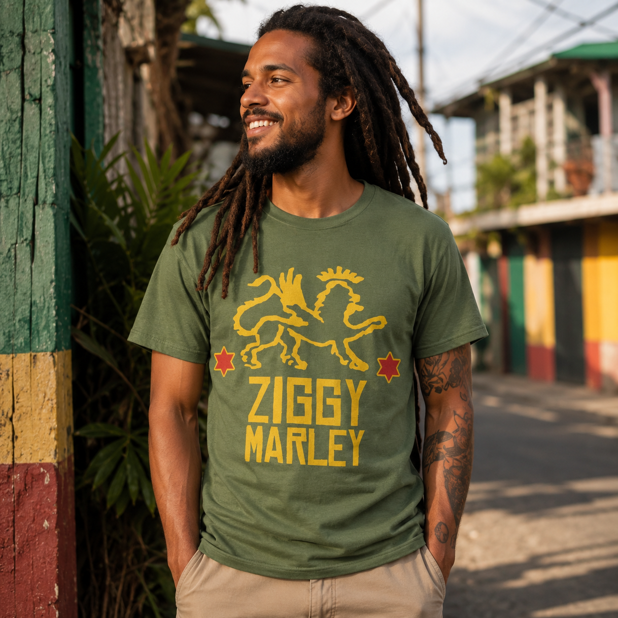 Male model wearing the Ziggy Marley Red Star Lion military green t-shirt in a colorful reggae-inspired street setting with tropical surroundings and warm sunlight.